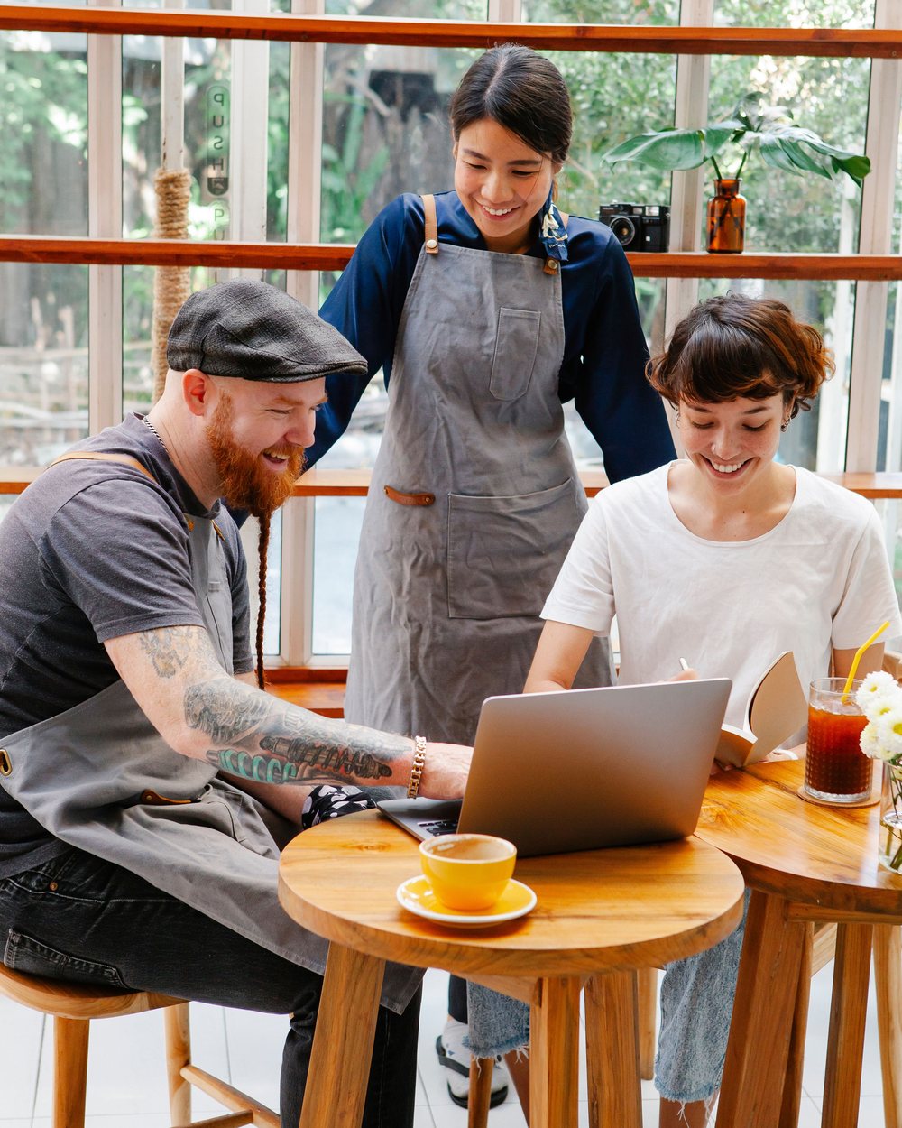 A cafe owner working the laptop while two others look on